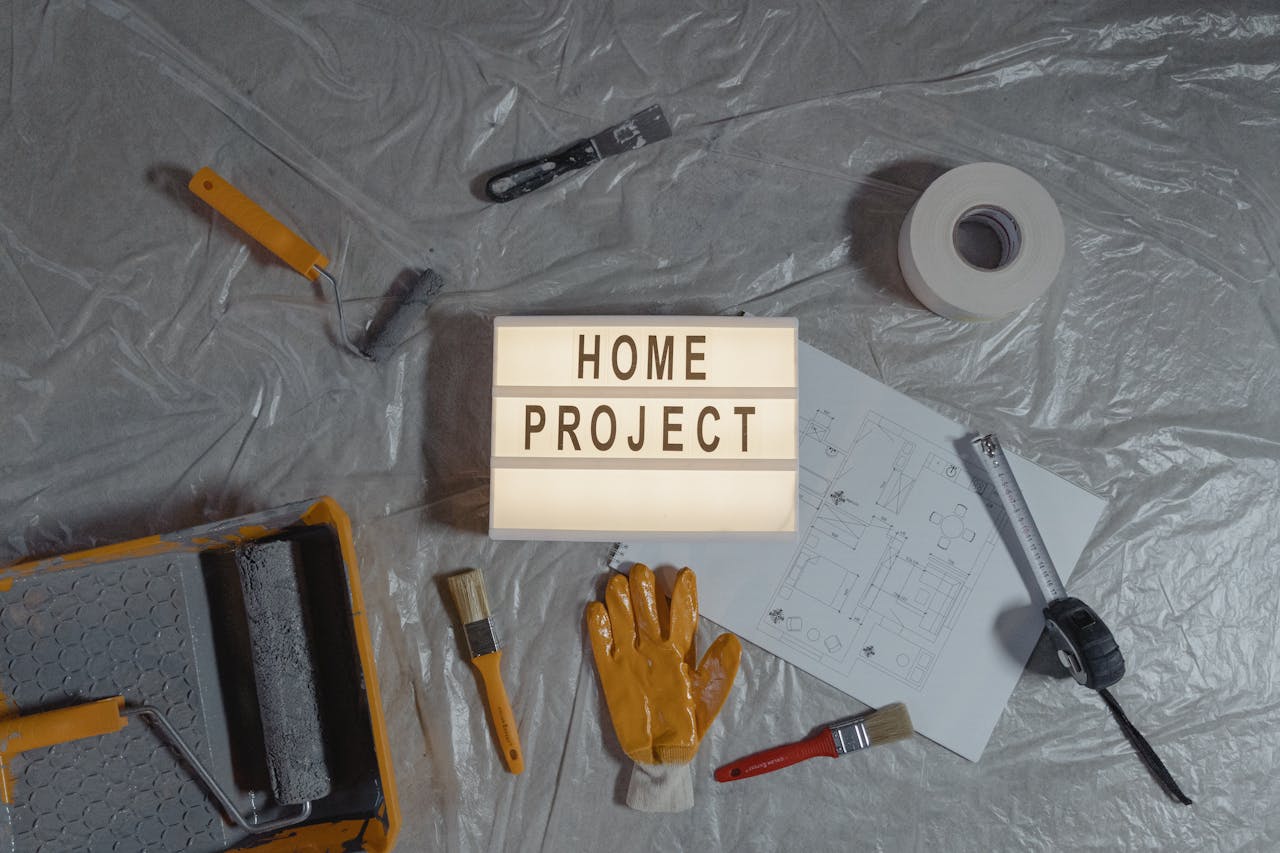 Flat lay of home improvement setup with tools, gloves, and floor plan for DIY projects.